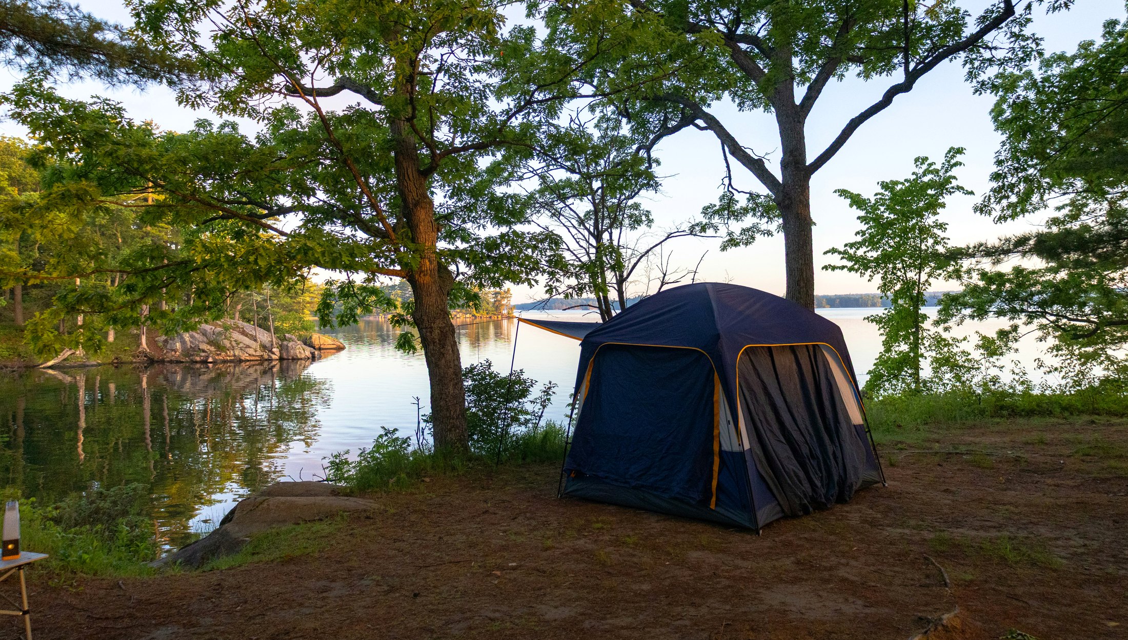Lakeside tent campsite surrounded by trees in New York
