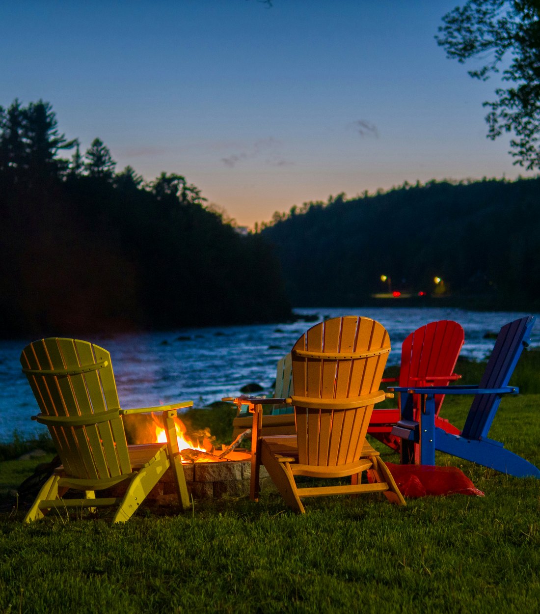 Adirondack chairs gathered around a fire pit at dusk in Maine